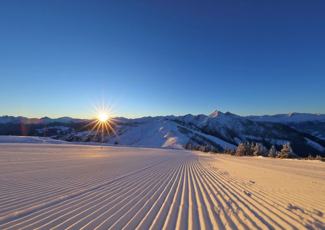 Sonnenaufgang über einer perfekt präparierten Piste im Großarltal